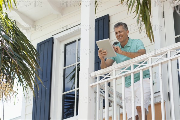 Caucasian man using digital tablet on balcony