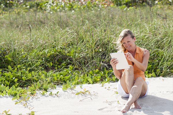 Caucasian woman using digital tablet on beach