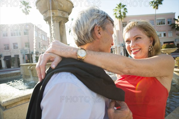 Older Caucasian couple hugging near fountain