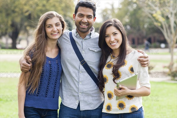 Smiling friends hugging in park