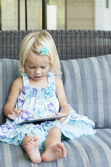 Caucasian girl using digital tablet on sofa