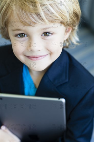 Smiling Caucasian boy in business suit holding digital tablet