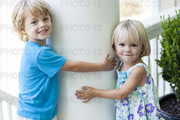 Caucasian children hugging column outdoors