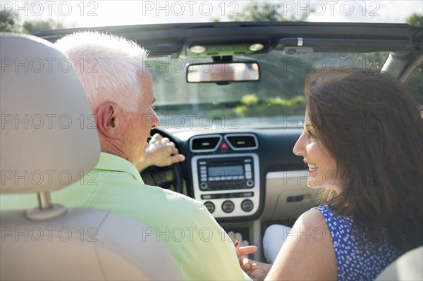Older Caucasian couple driving in convertible