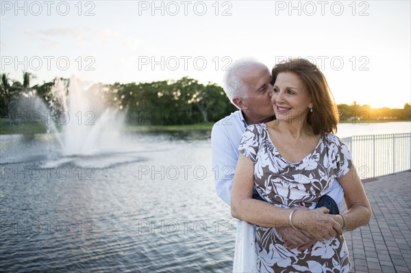 Older Caucasian couple hugging by fountain