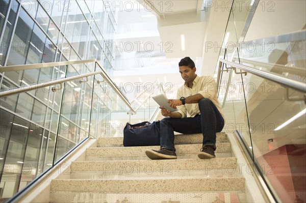 Asian businessman using digital tablet on office staircase