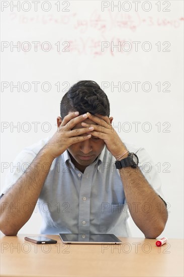 Frustrated Asian businessman with digital tablet and cell phone