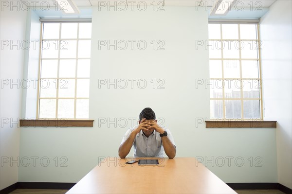 Frustrated Asian businessman using digital tablet in office