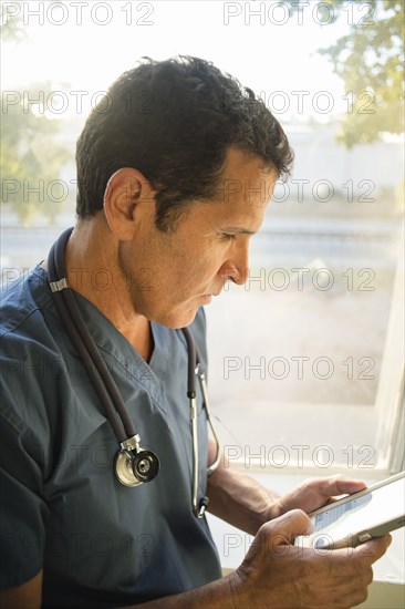 Hispanic doctor using cell phone near window