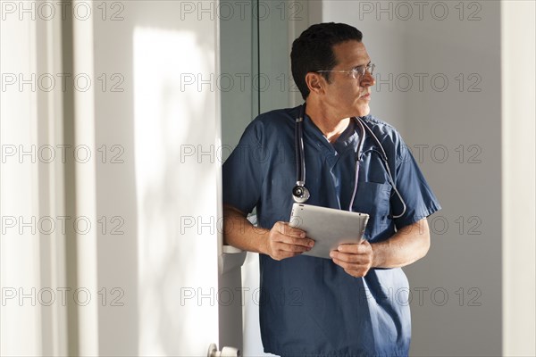 Hispanic doctor using digital tablet in hallway