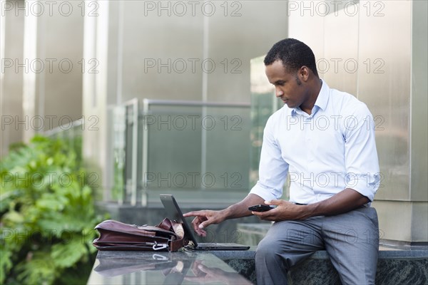 Black businessman using laptop outside building