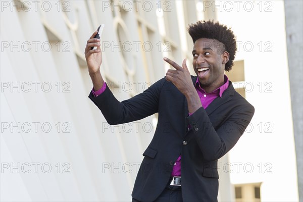 Black businessman taking selfie outside building