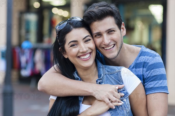 Hispanic couple hugging on city sidewalk