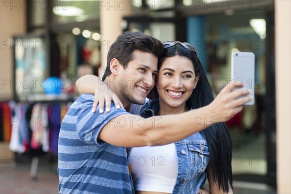 Hispanic couple taking selfie outdoors