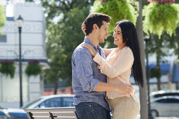 Hispanic couple hugging in urban park