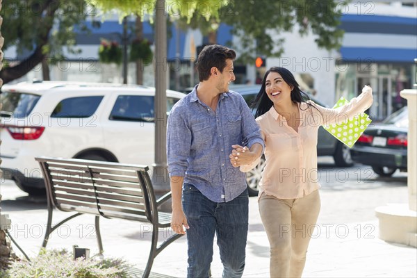 Hispanic couple walking on city sidewalk