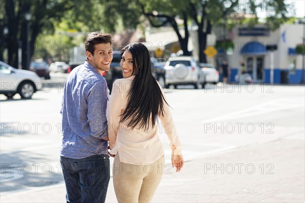 Hispanic couple walking on city sidewalk