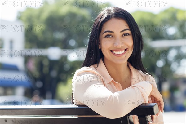 Hispanic woman smiling on bench