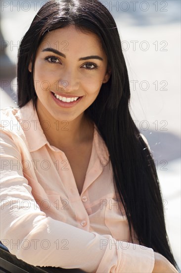 Hispanic woman smiling on bench