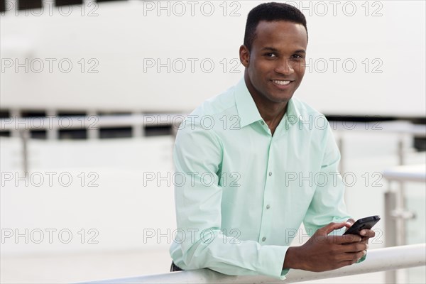 Black businessman using cell phone on balcony