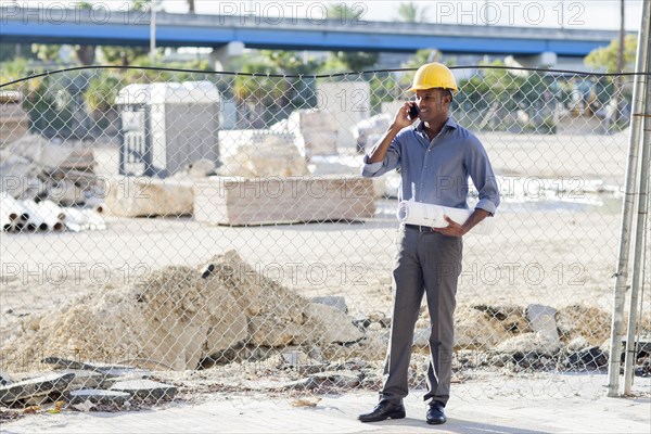 Black architect in hard hat talking on cell phone