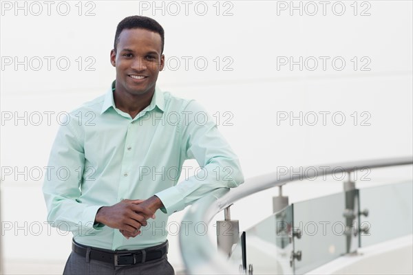 Black businessman leaning on railing