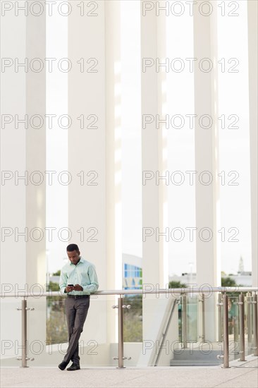 Black businessman using cell phone at railing