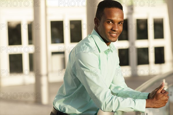 Black businessman leaning on railing