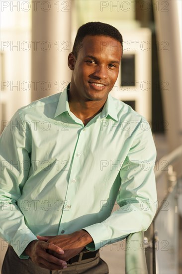 Black businessman leaning on railing