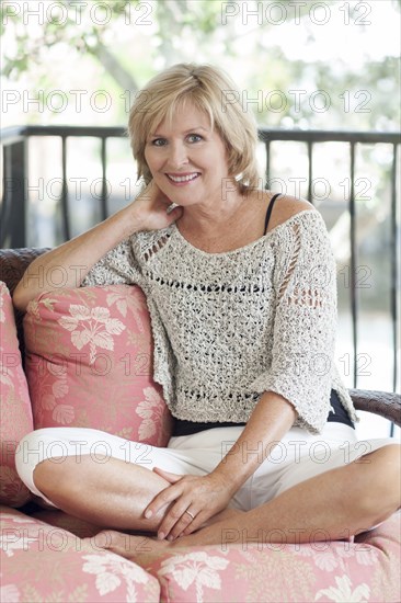 Smiling Caucasian woman sitting cross-legged on sofa