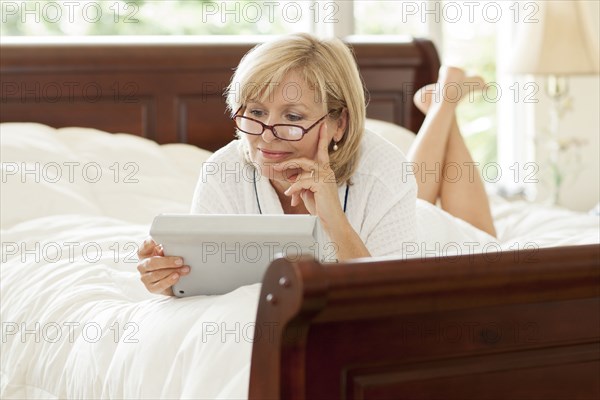 Caucasian woman using digital tablet on bed