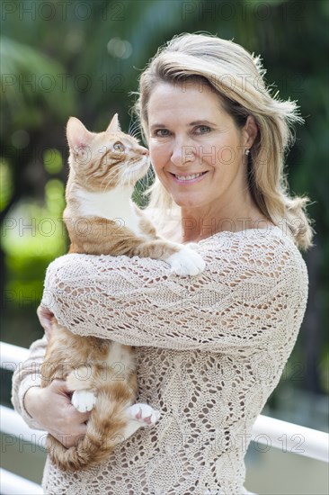 Smiling Caucasian woman holding cat outdoors