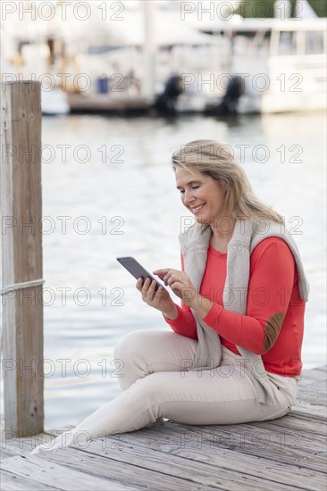 Caucasian woman using digital tablet on harbor dock