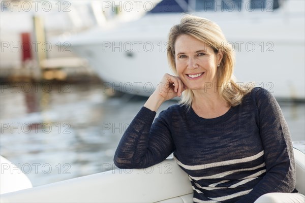 Caucasian woman sitting on boat in harbor