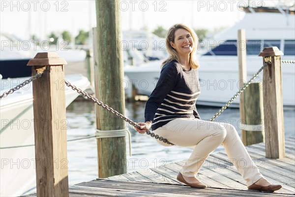 Caucasian woman sitting on dock in harbor