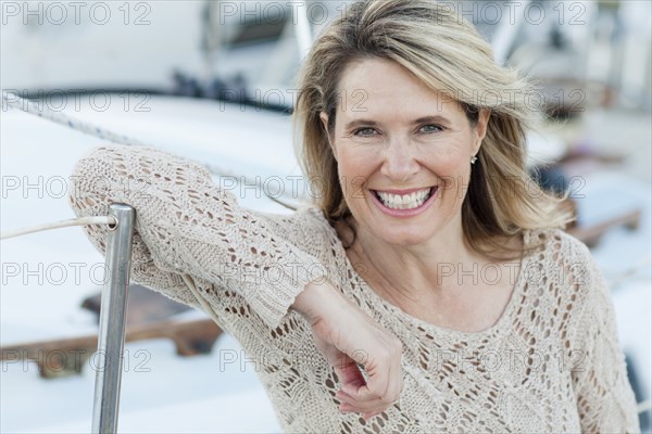 Caucasian woman leaning on boat in harbor