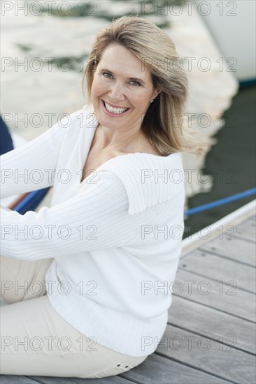 Smiling Caucasian sitting on deck in harbor