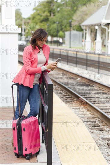 Mixed race woman using cell phone at train station