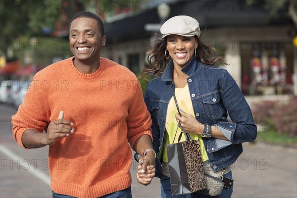 Couple holding hands and walking on sidewalk