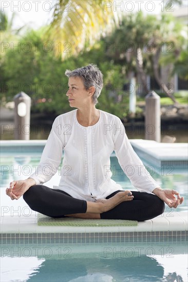 Woman meditating by still swimming pool