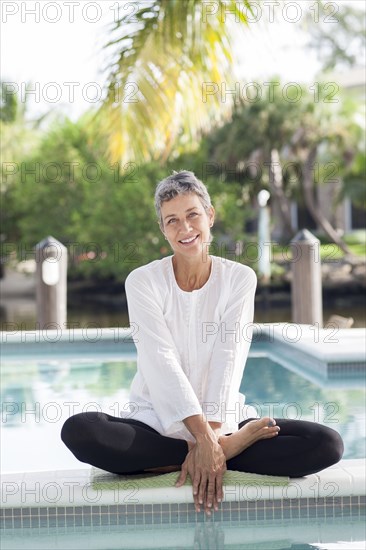 Woman sitting by still swimming pool