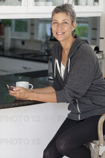 Woman using cell phone in kitchen