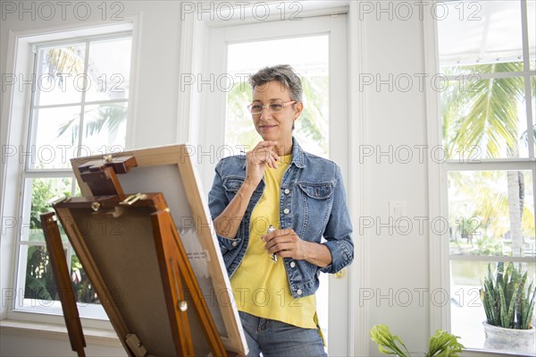 Artist painting on easel in sun room