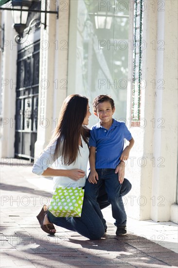 Caucasian mother and son hugging on sidewalk