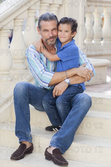 Caucasian father and son hugging on front stoop