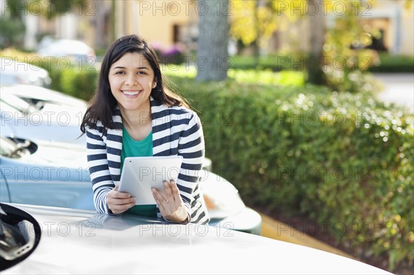 Hispanic woman using digital tablet in parking lot