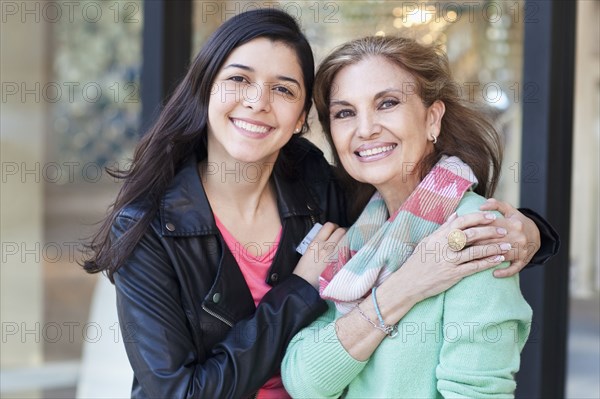 Mother and daughter hugging outside store