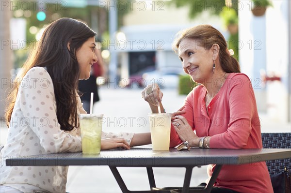 Mother and daughter drinking lemonade at sidewalk cafe