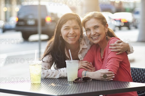 Mother and daughter hugging at sidewalk cafe