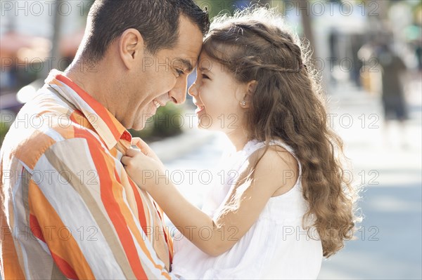 Close up of Hispanic father and daughter touching foreheads